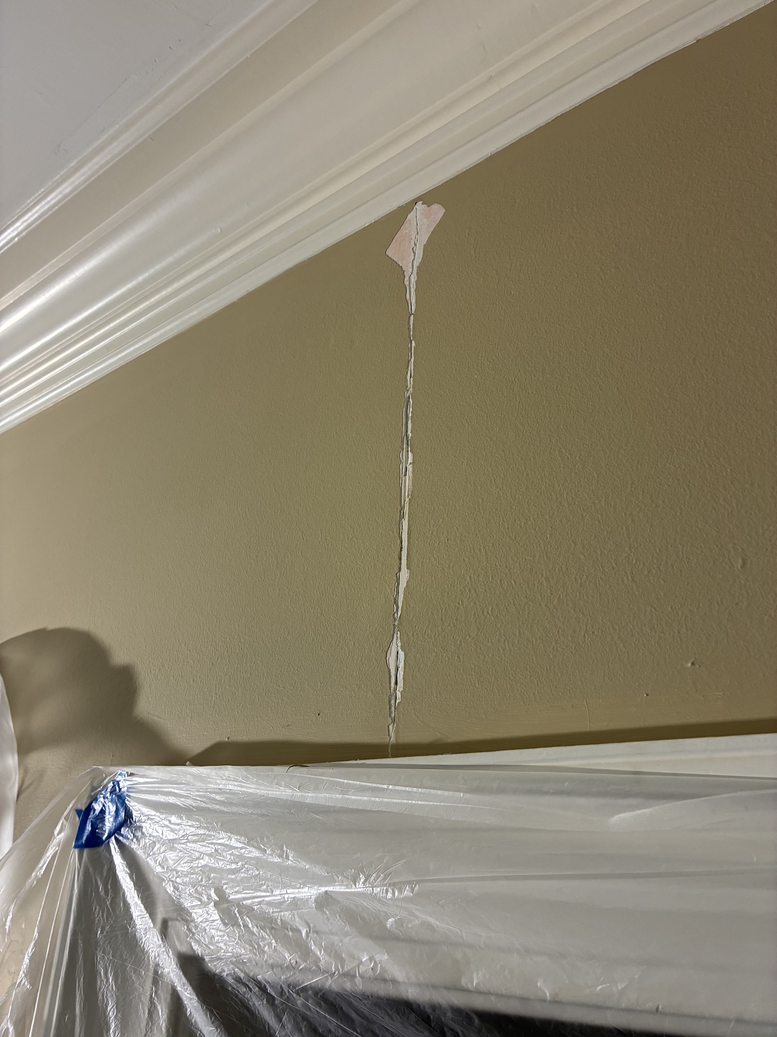 Loose drywall compound removed from a cracked joint above a door