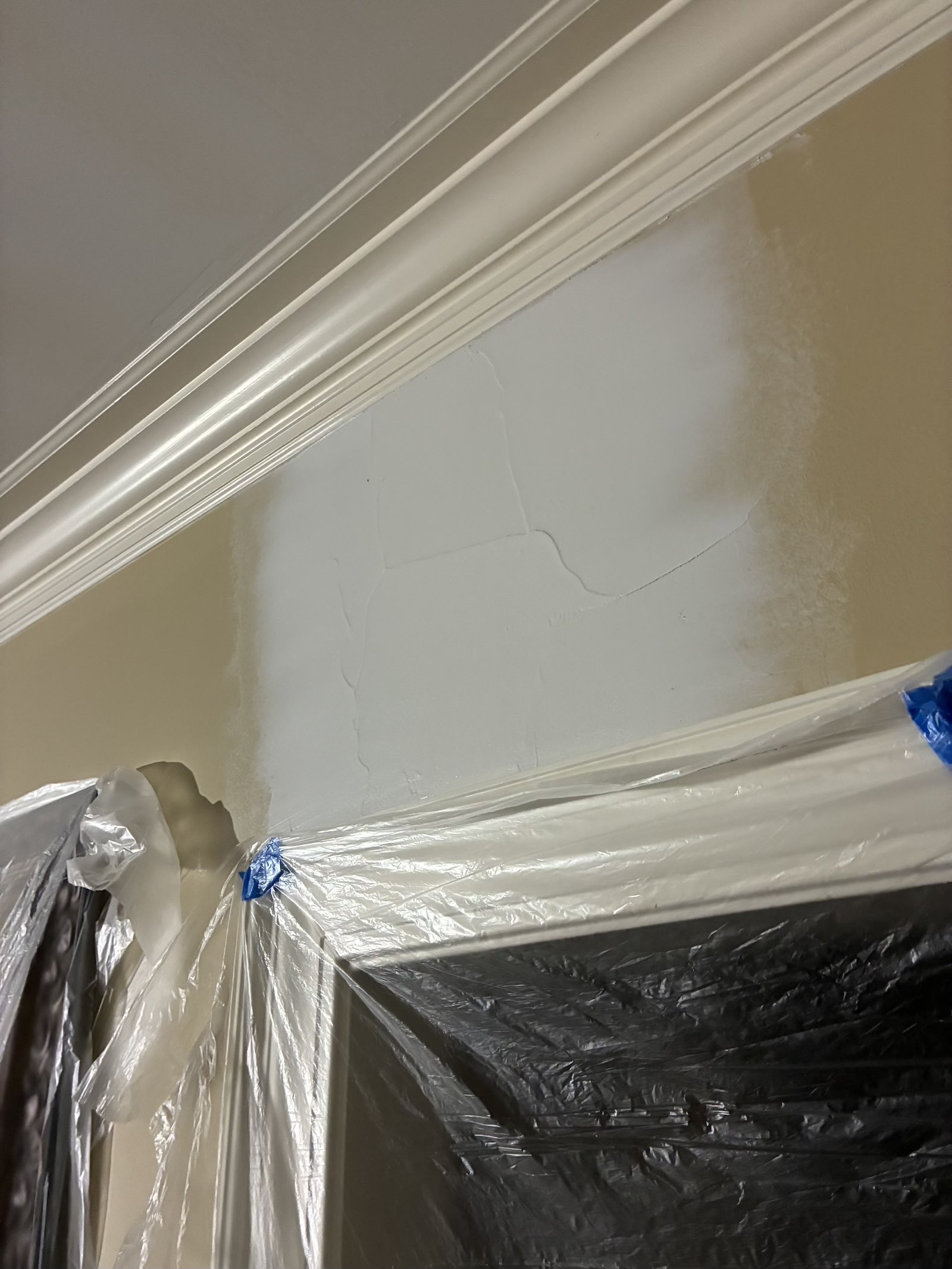 Second coat of joint compound feathered wide around a repaired drywall seam above a door